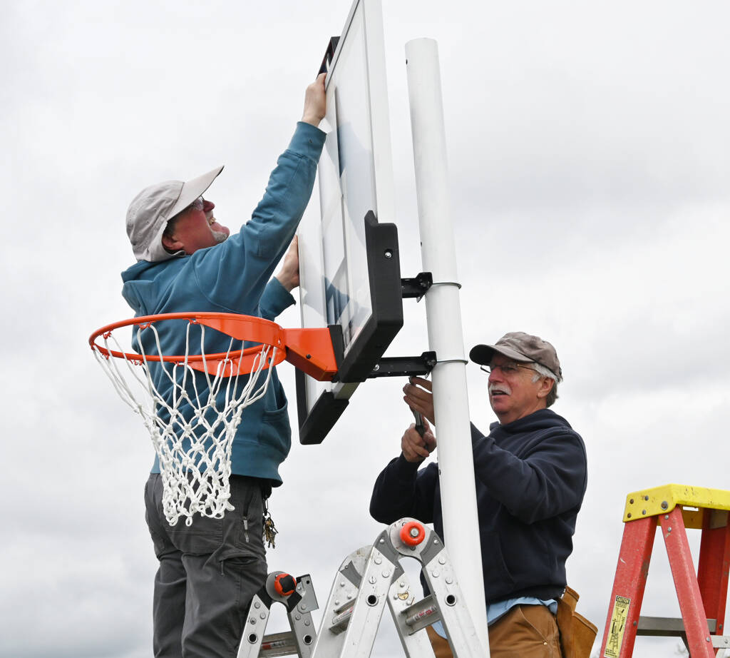 Steve Gilstrom, left, and Mark Holloway put up a basketball hoop at Helen Haller Elementary School’s playground on Beautiful Day, April 30.