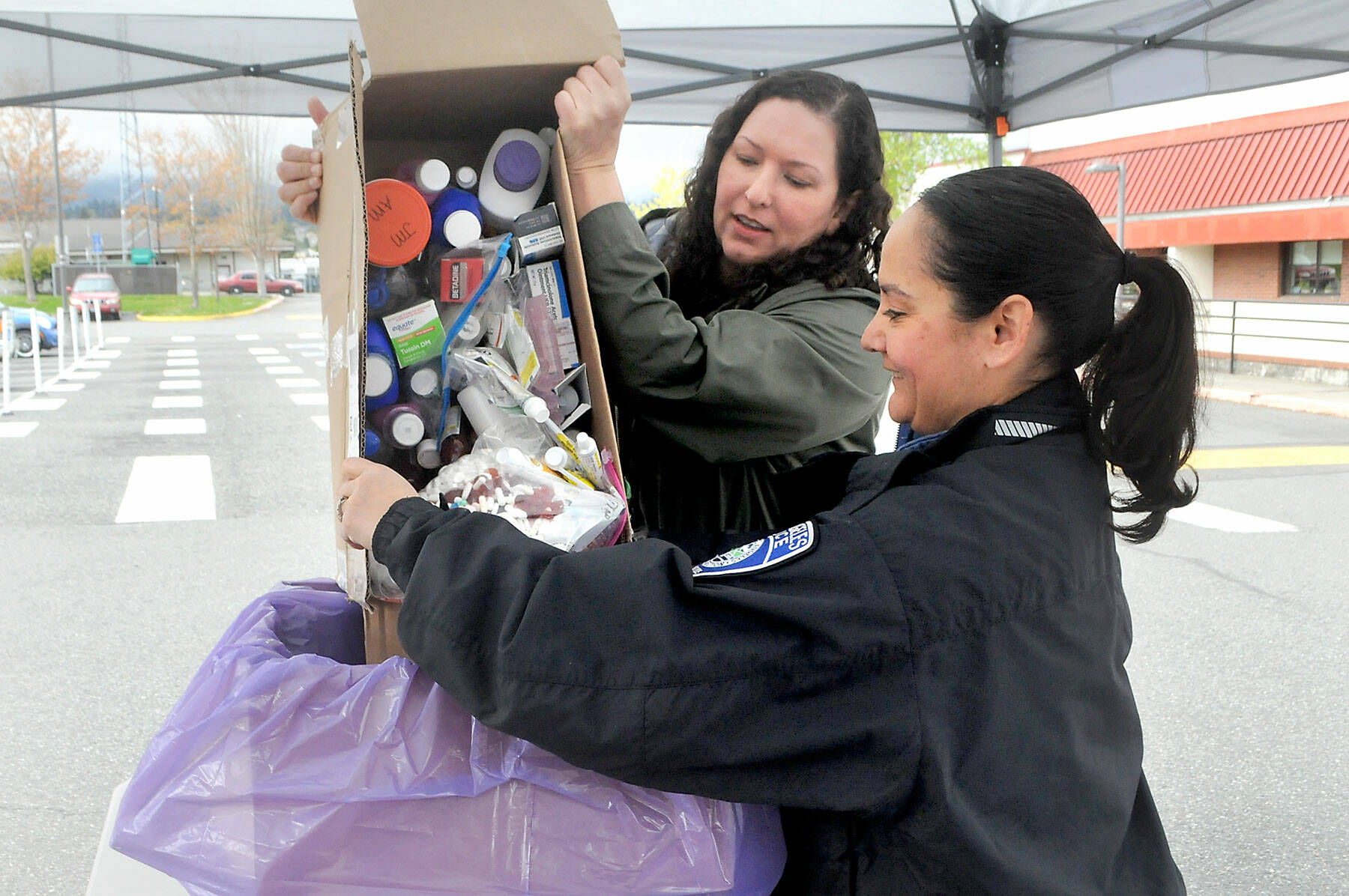 Keith Thorpe/Olympic Peninsula News Group
Nicole Salim, evidence manager for the Clallam County Sheriff’s Office, left, and Detective Swift Sanchez of the Port Angeles Police Department dump medicines into a collection box during National Prescription Drug Take Back Day at a drop-off site at the Clallam County Courthouse in Port Angeles on April 30. At the event, people were allowed to anonymously bring in expired, unused and unwanted prescription drugs for safe disposal. Similar drop-off sites on the North Olympic Peninsula were held in Sequim, Quilcene and Port Hadlock. Inspector Joshua Ley, Target Zero Manager with the Clallam County Sheriff’s Office, said citizens delivered 258 pounds of unwanted, unused, and/or expired medications to the courthouse drop-off location.