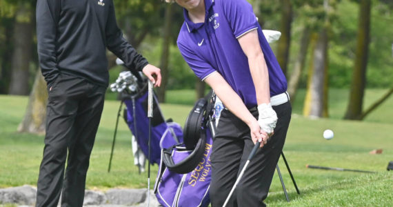 As teammate Dominic Riccobene looks on, Sequim's Ben Sweet hits a chip shot on the 11th hole in an April 28 Olympic League match against North Kitsap. Riccobene, Sweet and teammate Cole Smithson were slated to compete in the 2A state tournament this week in Olympia. Sequim Gazette file photo by Michael Dashiell