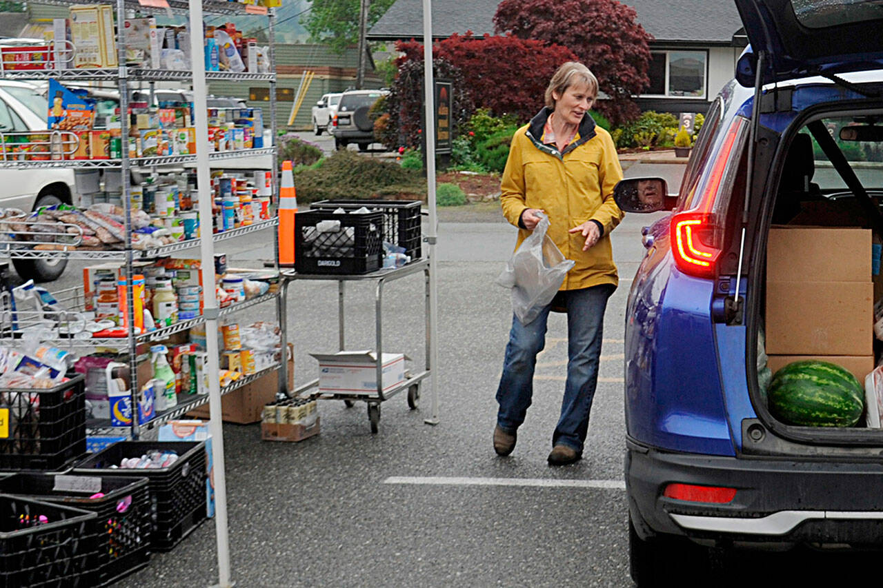 Sequim Gazette photo by Matthew Nash
Patti Winnop-Colwell, a long-time Sequim Food Bank volunteer, helps a visitor pick out some items from the facility’s drive-through on June 3.