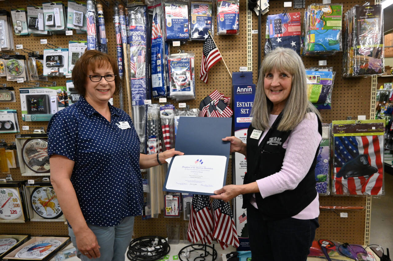 Kathy Reid, store manager at The Co-Op Farm & Garden, right, accepts a special honor from the Michael Trebert Chapter of the Daughters of the American Revolution’s vice regent, Anita Reynolds. The Co-Op, at 216 E. Washington St., was selected for to receive the National Society of the Daughters of the American Revolution Flag of the United States certificate for correct usage of the U.S flag, for “repeatedly demonstrating how to keep the flag flying and protect it continuously under all conditions.” The local honor was awarded on Flag Day, June 14, 245 years after the day U.S. leaders approved its first national flag. President Harry Truman in 1949 signed a bill officially recognizing June 14 as Flag Day. Sequim Gazette photo by Michael Dashiell
