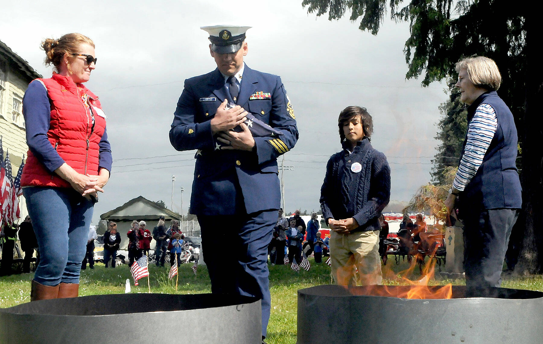 U.S. Coast Guard Chief Petty Officer Shane Thompson, accompanied by his son, Malachi Thompson, 10, a member Junior American Citizens, carries a used flag for incineration on June 14 at the Northwest Veterans Service Center in Port Angeles on Flag Day. Overseeing the burning were Ginny Sturgeon, left, and Jan Urfer, right, members of the Michael Trebert chapter of the Daughters of the American Revolution, which co-hosted the event with the Clallam County Veterans Association. Eleven used cotton flags were burned during Tuesday’s Flag Retirement Ceremony. Photo by Keith Thorpe/Olympic Peninsula News Group