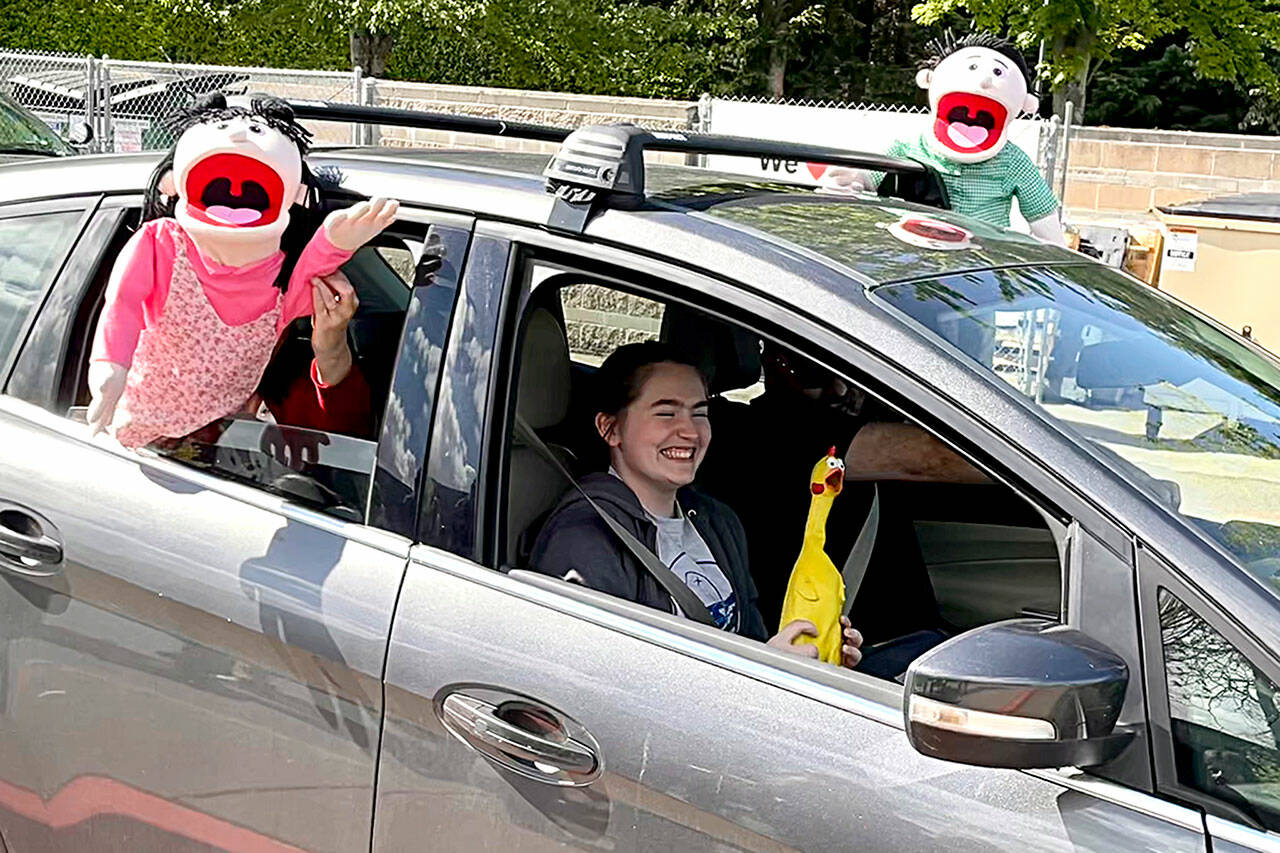 Sequim Gazette photos by Matthew Nash
Sequim Middle School student Emma Gilliam smiles as puppets — held by her parents Glenn and Kecia — cheer for her during the drive-through event celebrating eighth graders moving onto high school.