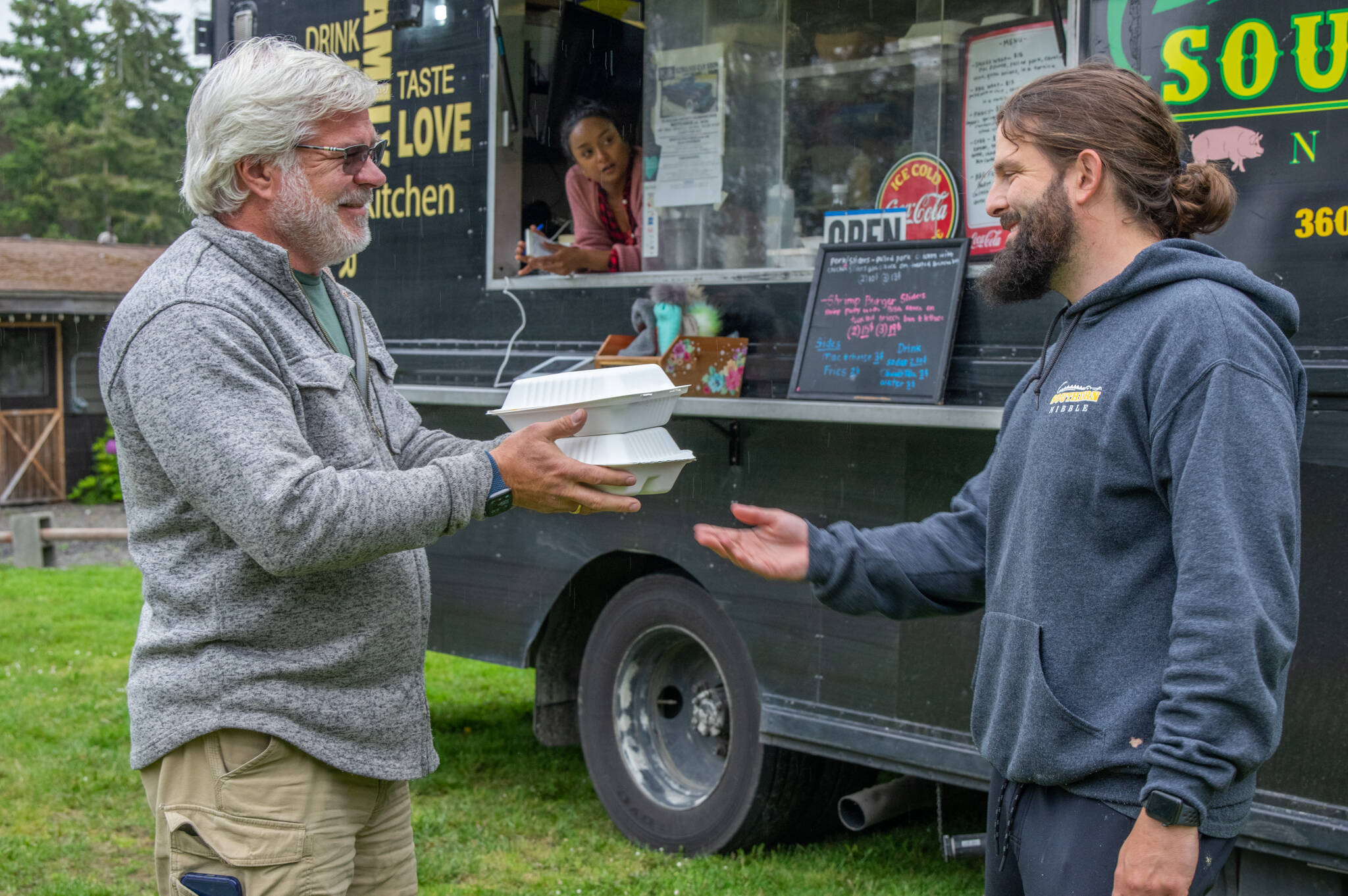 Jay Pederson, a full-time RV traveler, receives dinner for himself and his wife from Caleb Messinger at the Southern Nibble food truck, parked at the John Wayne Marina Resort on the outskirts of Sequim. Sequim Gazette photo by Emily MatthiessenSequim Gazette photo by Emily Matthiessen