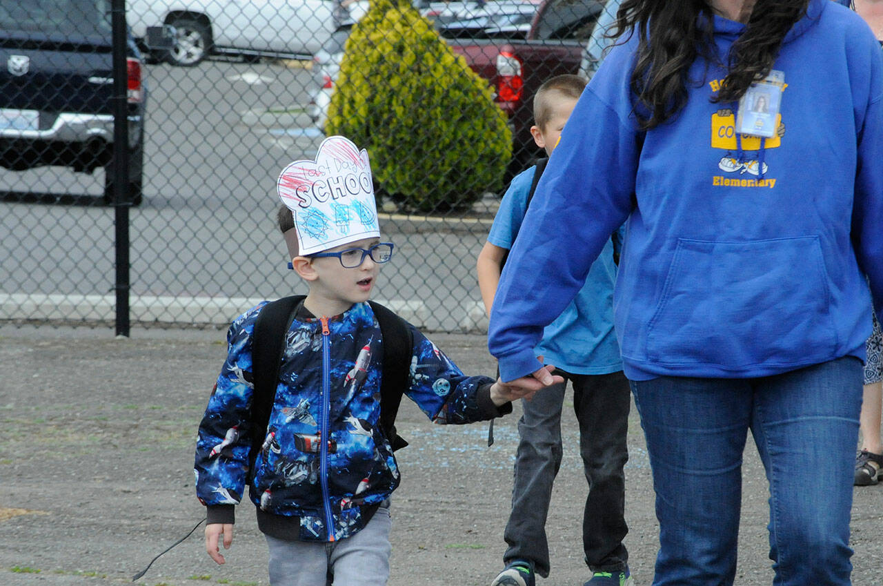 Teacher Tracy DeLorm walks first-grader Raylan Coler to the bus as he sports his “Last Day of School” crown at Helen Haller Elementary. Most of Sequim School District’s schools finished classes on June 17 for summer break.