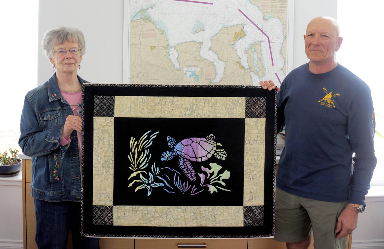Submitted photo / Mary Jeanne Richards and club Commodore Frank DeSalvo of the Sequim Bay Yacht Club display "The Spirit of Honu," a quilt being raffled by the club to raise funds for Volunteer Hospice of Clallam County respite care services.
