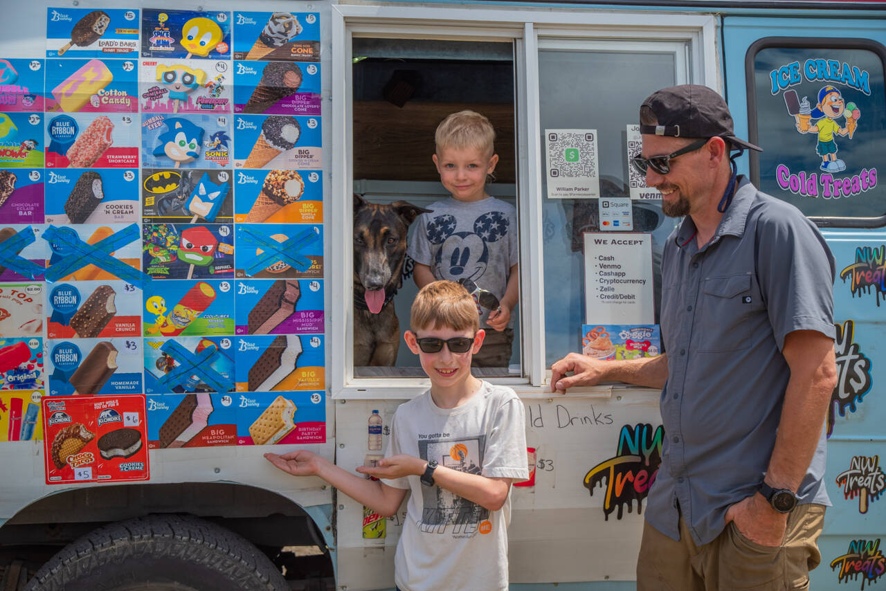 From left to right, Mr Orange and Justin, Charlie and Joe Parker pause inside and outside their ice cream truck in Sequim last Saturday. Northwest Treats has no fixed route, but travels all over Sequim and Port Angeles and in between and as far as Lake Sutherland and the lower Elwha. Joe Parker says that “people message us to come by,” using text, instagram and Facebook. Sequim Gazette photo by Emily Matthiessen