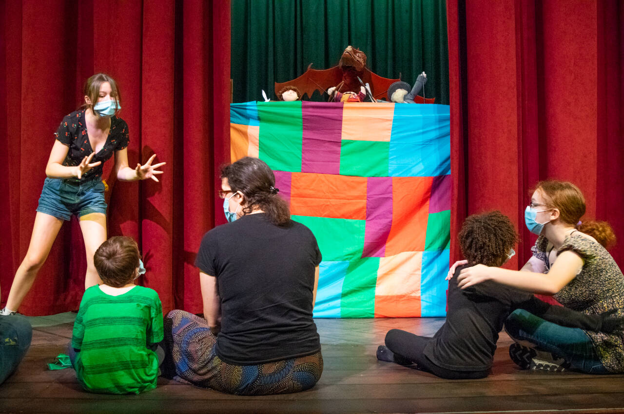 Roxy Woods, a wizard/storyteller, entertains a small hobbit crowd in the first scene of Olympic Theatre Arts’ upcoming production, “The Hobbit.” The puppet show mirrors latter scenes in which giant puppets interact with the cast. From left to right: Woods, Wally McCarter (Hobbit Child), Amber McCarter (Hobbit Mother), Egan Owie (Hobbit Child), Chloe Loucks (Hobbit Mother). The hand puppets were created by Curt White. Sequim Gazette photo by Emily Matthiessen