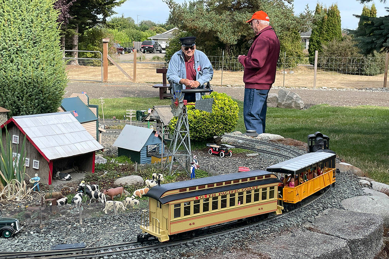 Sequim Gazette photo by Matthew Nash/ Dick Wolf of Sequim chats with Alan Melrose of Kent during a club tour of Wolf’s garden railroad for the Puget Sound Garden Railway Society on Sept. 17. Wolf and his wife Evelyn started with G-scale (garden) trains in 1999 after discovering a magazine about the hobby, Dick said.