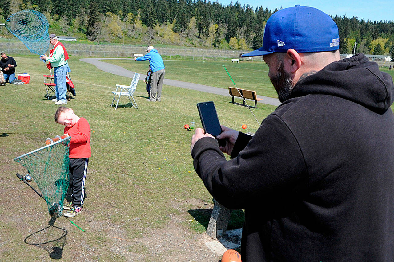 Sequim Gazette photo by Matthew Nash
Terry Wopperer snaps a photo of his son Bentley’s first fish at the Kids Fishing Day in April 2022. The event will continue in April 2023 but fish will only be stocked that weekend due to concerns over warm pond temperatures.