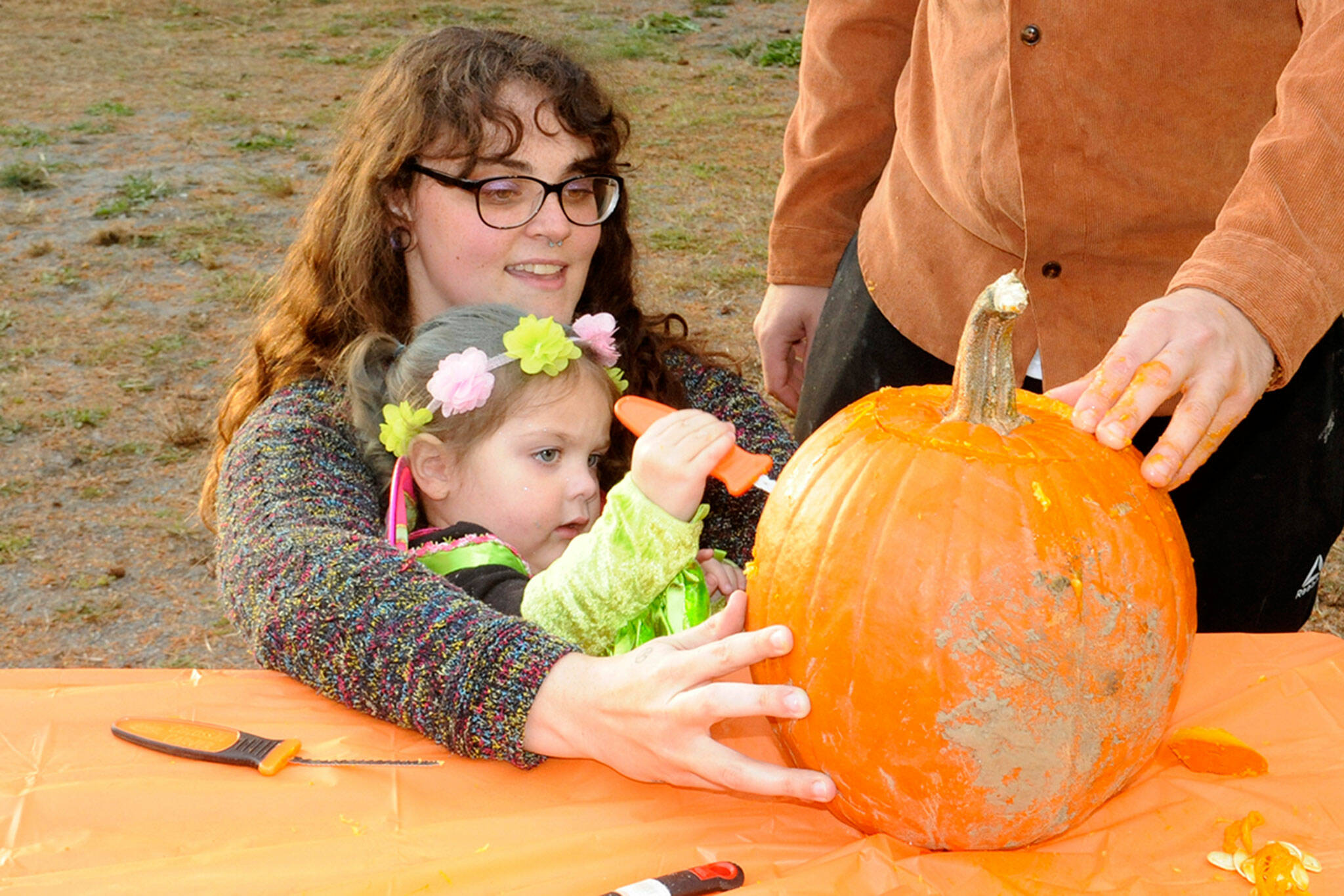 Sequim Gazette photo by Matthew Nash/ Two-and-a-half-year old Poppy Springer carves a pumpkin dressed as a fairy with help from mom Sierra Perdue during the Sequim Prairie Grange’s Trunk-or-Treat.
