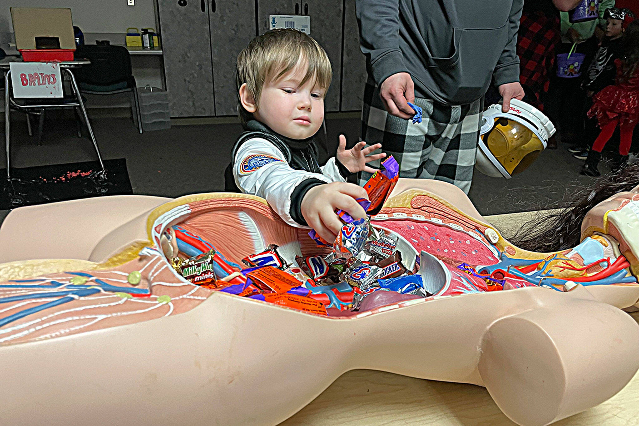 Sequim Gazette photo by Matthew Nash/ Spaceman Tucker Weatherly, 4, enjoys some treats from a dummy’s tummy inside during Sequim High School’s Haunted Hallways event on Oct. 29. The HOSA club, now known as Future Health Professionals, offered gloves for children to wear and touch “brains,” and other body parts.