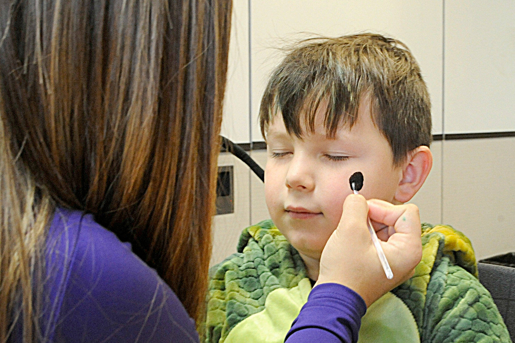 Sequim Gazette photo by Matthew Nash/ Five-year-old Bowie Dockery gets a spider painted on his face by Azalea Loveday, 14, at the Sequim High School Haunted Hallways event. Loveday was one of many cheerleaders offering festive face painting.