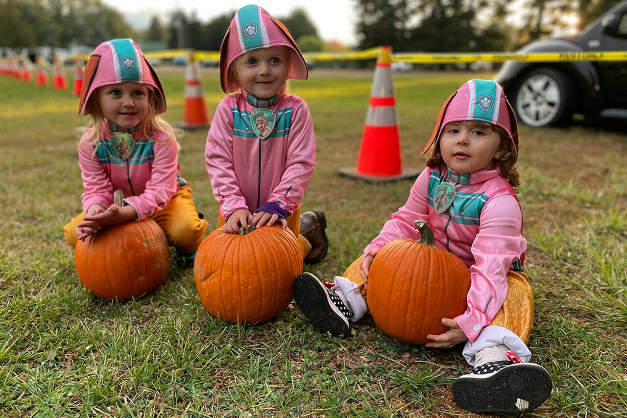 Sequim Gazette photo by Matthew Nash
The Paw Patrol’s Liberty dog was on the scene in triple time at the Sequim Prairie Grange’s Trunk-or-Treat on Oct. 29 with, from left, Madalyn, 3-and-a-half, and Jordyn Robotkay, 2-and-a-half, and Oakley Seimer, 3, all of Sequim. The trio all received pumpkins from the grange and their moms planned to take them home to carve. See more pre-Halloween photos on A-11.
