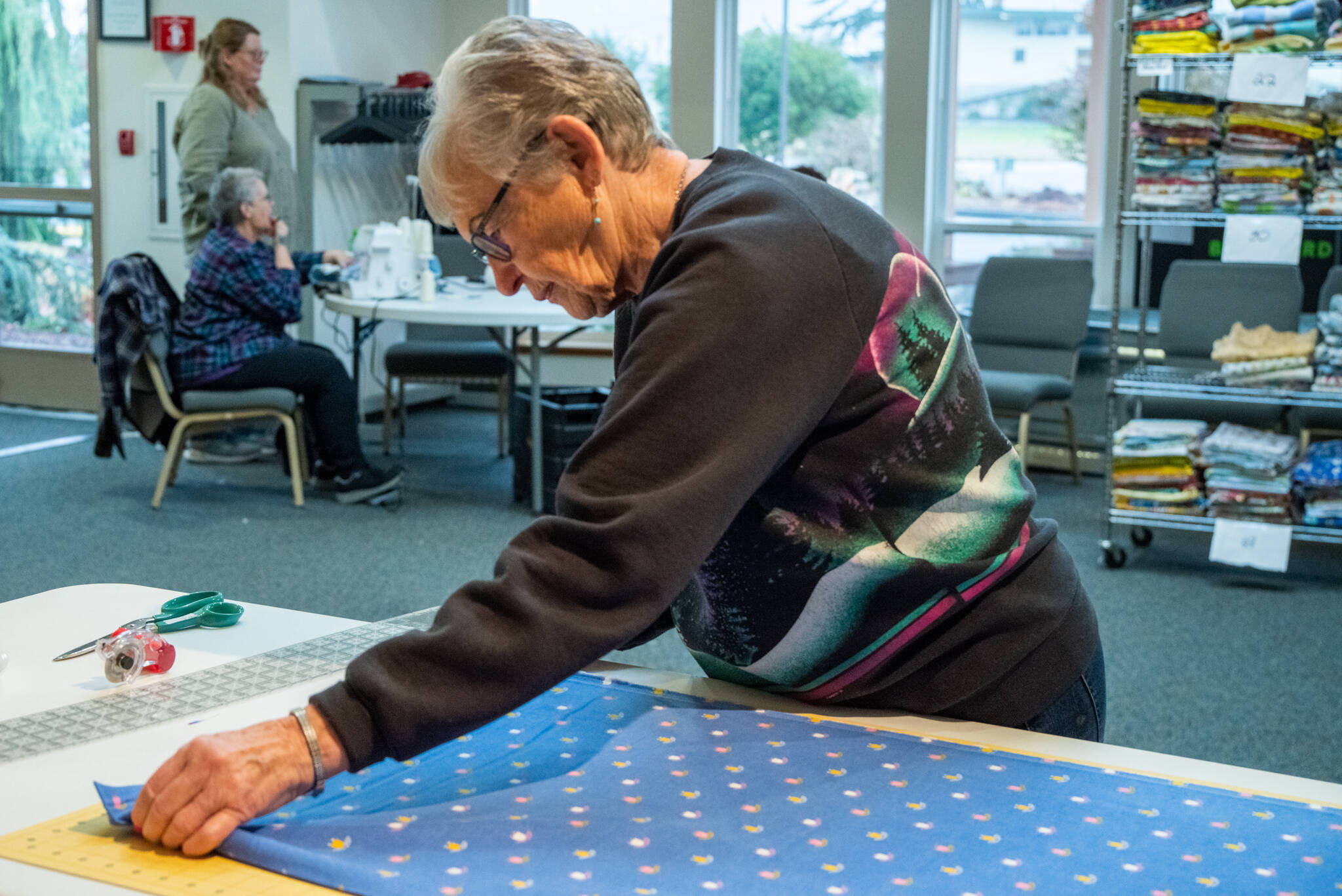 Sequim Gazette photo by Emily Matthiessen / Betty Zander prepares a piece of flannel fabric for cutting to be made into blankets by the Sequim Serger Squad, , which is seeking new volunteers and donations in their quest to provide blankets to children locally and globally.