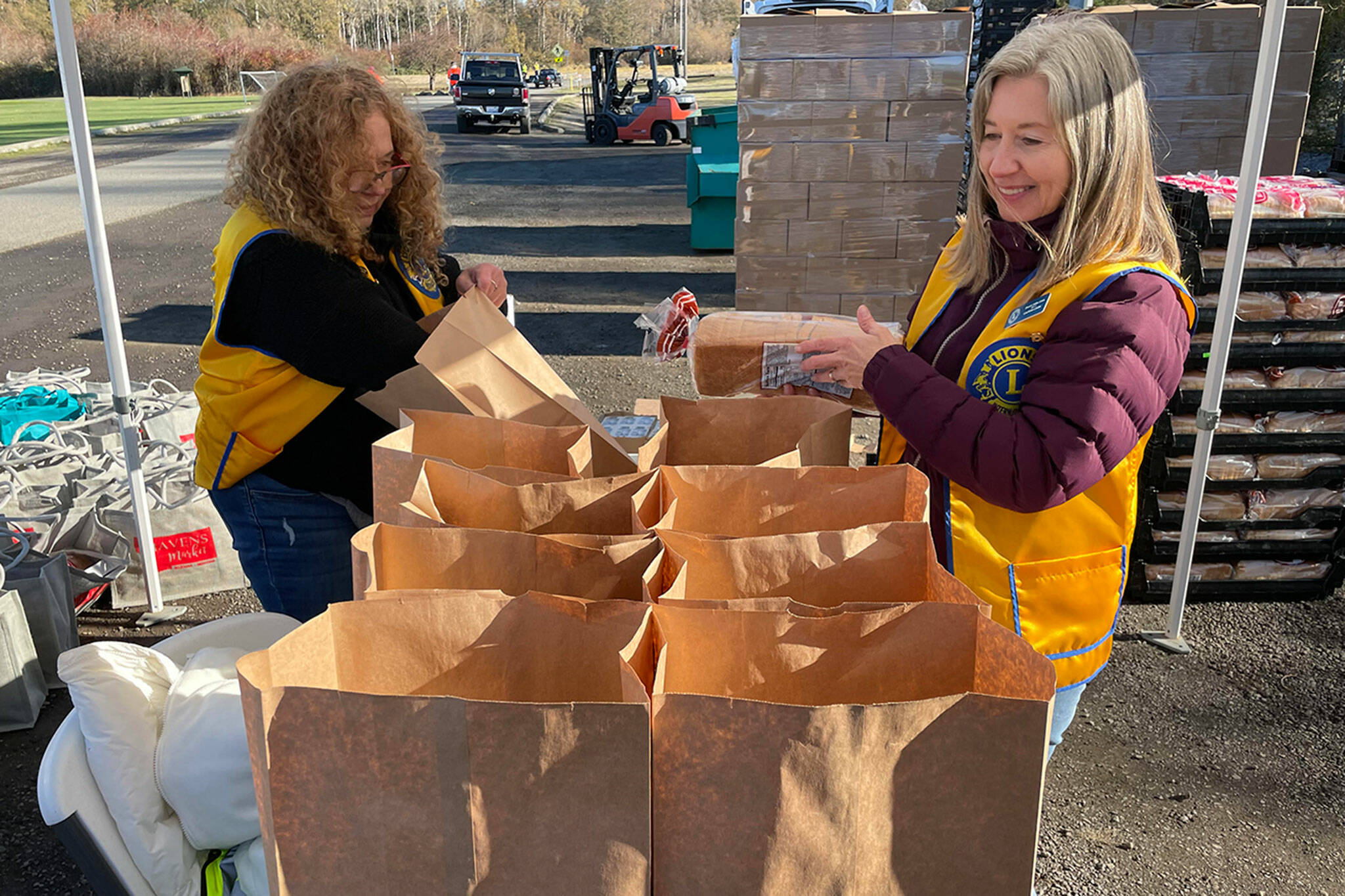Sequim Gazette photo by Matthew Nash/ Denice Irish, on left Lou Ann Linder with the Sequim Valley Lions bag bread and other items for the Family Holiday Food Bag Distribution day on Nov. 18 in Carrie Blake Community Park.