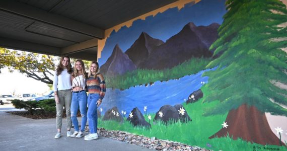 Sequim Gazette photo by Michael Dashiell / Sequim High students Kari Olson, Hi’ilei Robinson and Claire D’Amico stand beside the mural they’ve created on the campus’ C building wall.
