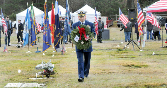 Cmdr. Brian Tesson, commanding officer of the U.S. Coast Guard Cutter Active, carries a wreath for the grave of Coast Guard veteran Harold Hanusa, who served during World War II, during Saturday's Wreaths Across America ceremony at Mount Angeles Memorial Park in Port Angeles. The event, part of a national initiative to honor veterans of military service, saw individual branches of the military recognized during the ceremony followed by the placement of more than 2,300 wreaths for servicemen and women at six cemeteries across the North Olympic Peninsula. (Keith Thorpe/Peninsula Daily News)