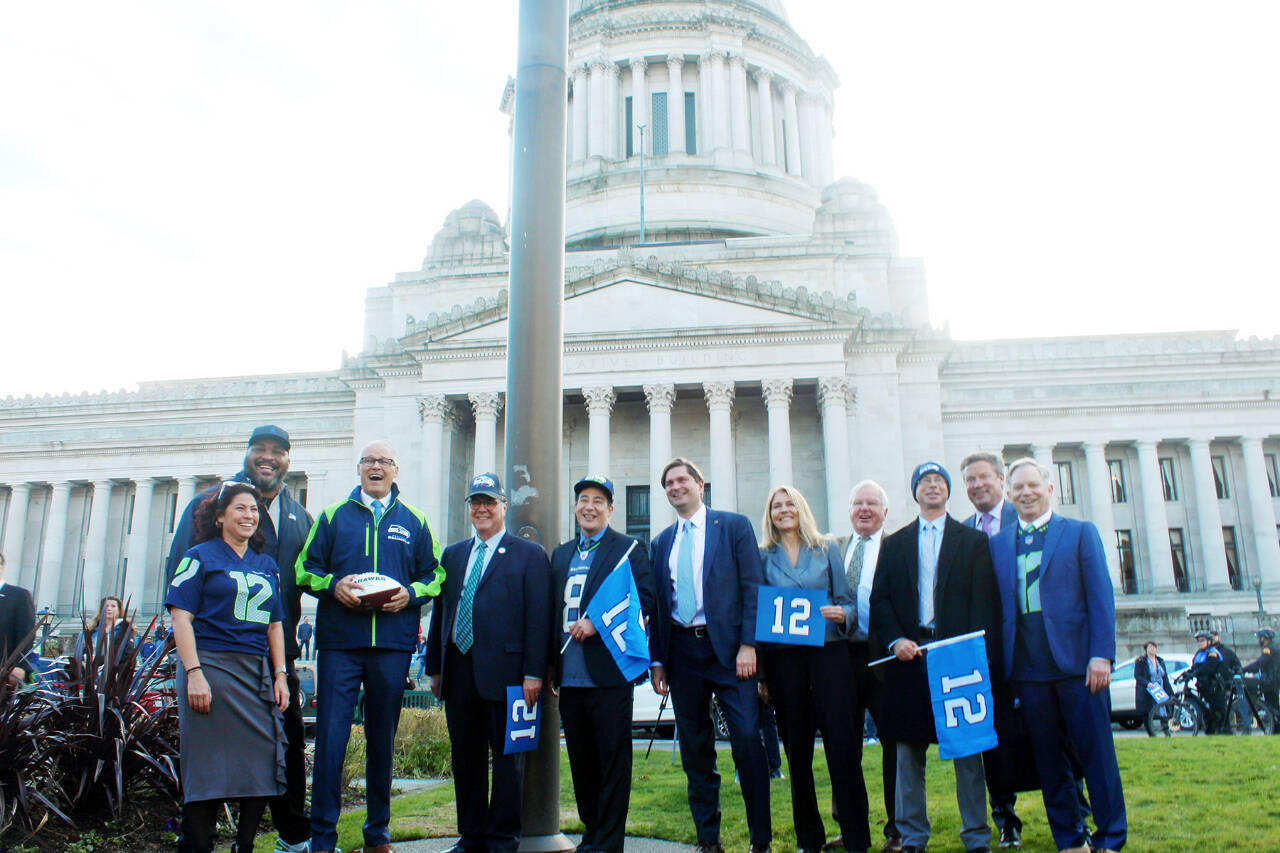 Photo by Reneé Diaz/WNPA News Service / Gov. Jay Inslee, Secretary of State Steve Hobbs and other Washington lawmakers stand in front of the legislative building with Seahawks star Walter Jones after raising the 12th-man flag on Jan. 11.