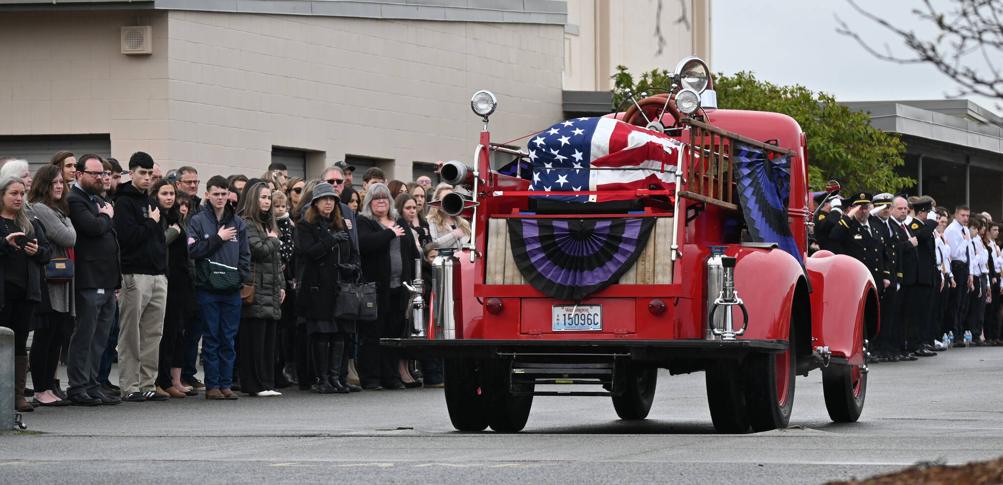 Sequim Gazette photos by Michael Dashiell
Attendees of the Jan. 21 memorial for Capt. Charles “Chad” Cate look on as the antique fire truck transporting Cate’s coffin arrives at Sequim High School.