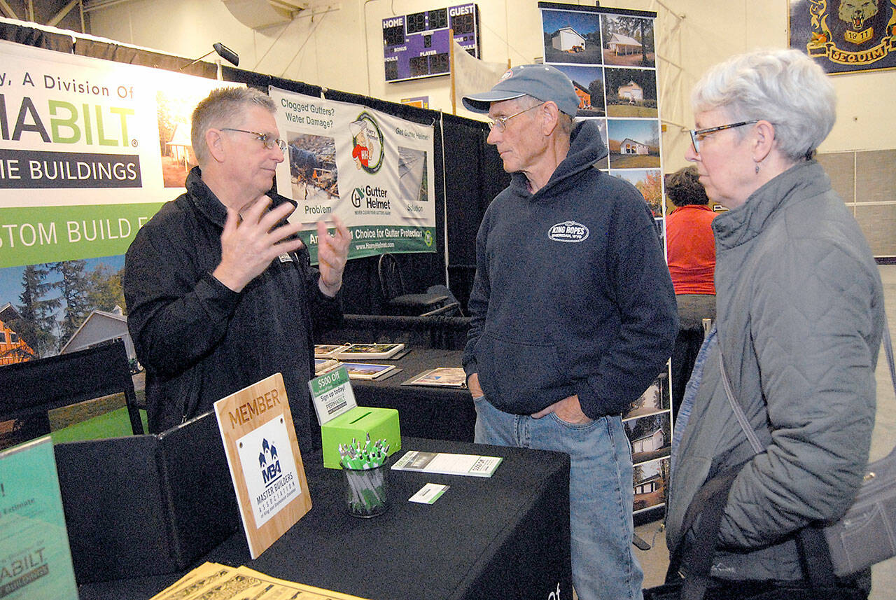 File photo by Keith Thorpe/Olympic Peninsula News Group / Will Johnson of Lynnwood-based PermaBilt Post Frame Buildings, left, speaks with Brad and Marla Varner of Sequim at his company’s booth at North Peninsula Building Association’s Building, Remodeling and Energy Expo in 2019. NPBA hosts a LEGO building challenge at this year’s event, set for Feb. 19.