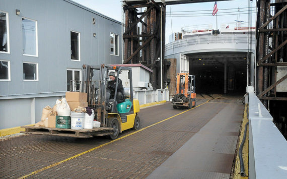 Able seamen Doug Reader, front, and Brandon Melville drive forklifts as they offload equipment from the ferry MV Coho after its return to Port Angeles from annual dry dock maintenance in Anacortes on Wednesday. The ferry is scheduled to resume regular service between Port Angeles and Victoria today. (Keith Thorpe/Peninsula Daily News)