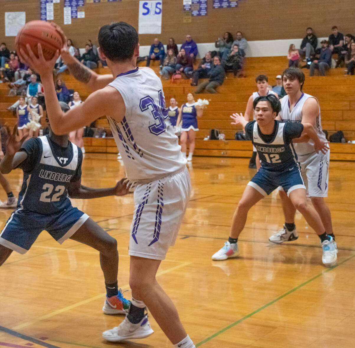 Sequim Gazette photo by Emily Matthiessen / Sequim’s Isaiah Moore (34) looks to pass to teammate Espn Judd as Lindbergh’s John Chuol (22) and Justin Tu (12) defend in a Feb. 15 West Central District tournament game in Sequim. The Wolves’ topped Lindbergh, 66-37.