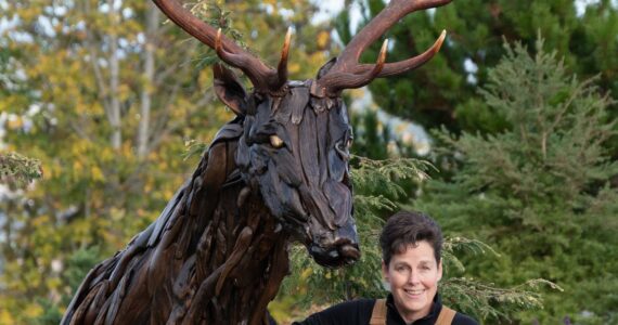 Photo courtesy of Molly Omann 
Olympic Peninsula artist Molly Omann stands near a 9-foot-tall elk she created from driftwood.