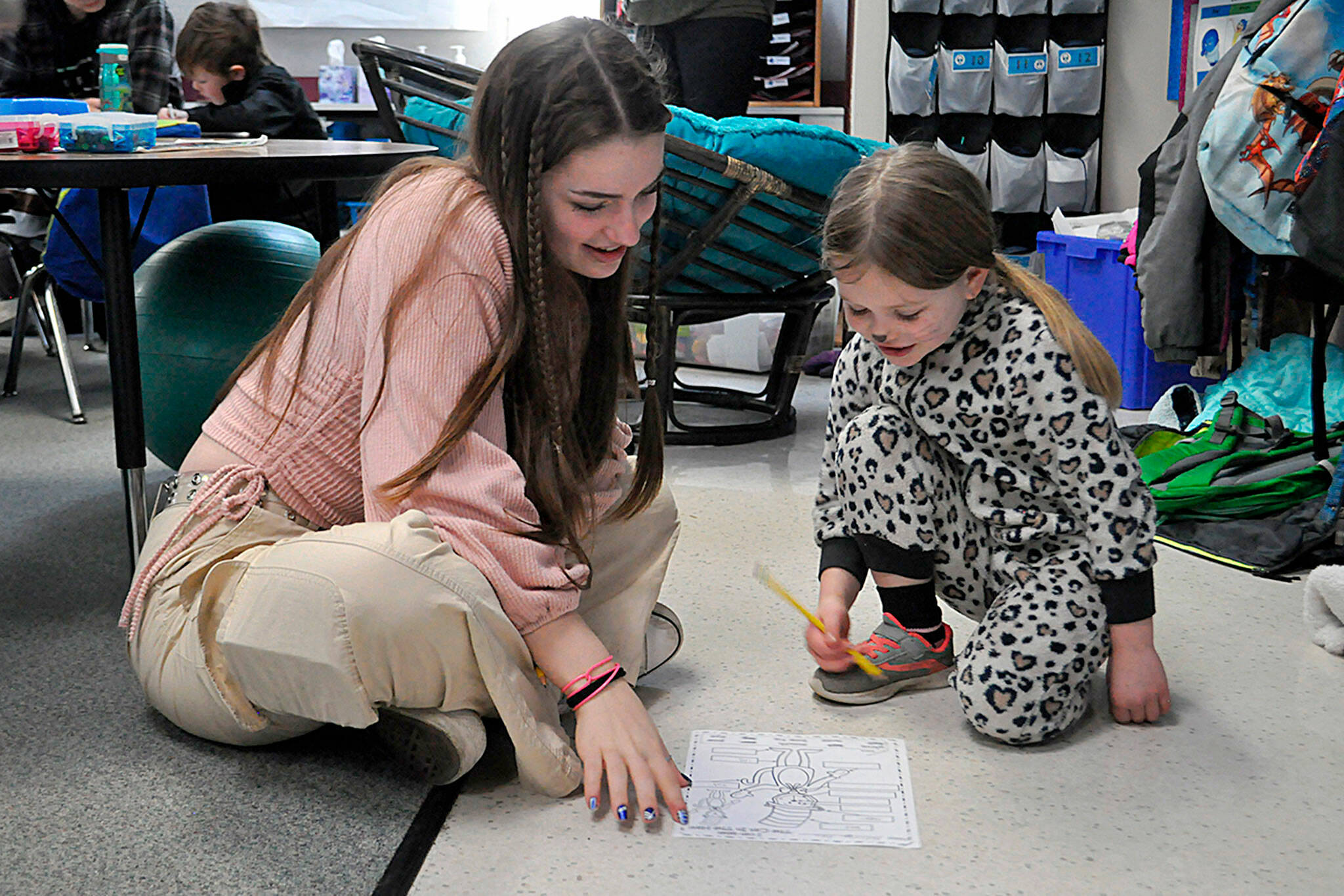 Sequim Gazette photo by Matthew Nash/ Eighth grader Ava Shinkle works with first grader Mavery Abken on a Dr. Seuss-inspired word work sheet on March 2 in Dawn Downs’ classroom at Greywolf Elementary. Sequim Middle School students traveled in the afternoon to read, draw and work with Greywolf students.