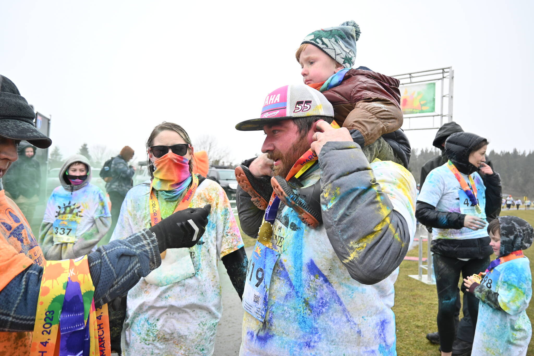 Sequim Gazette photos by Michael Dashiell
Artem Cummings, nearly 3, gets a piggyback ride from dad Dillon Cummings as mom Shelbie looks on, following the Sun Fun Color Run on March 4. The Cummings were part of a large family contingent who braved the chilly weather and rain/sleet/snow for the race.