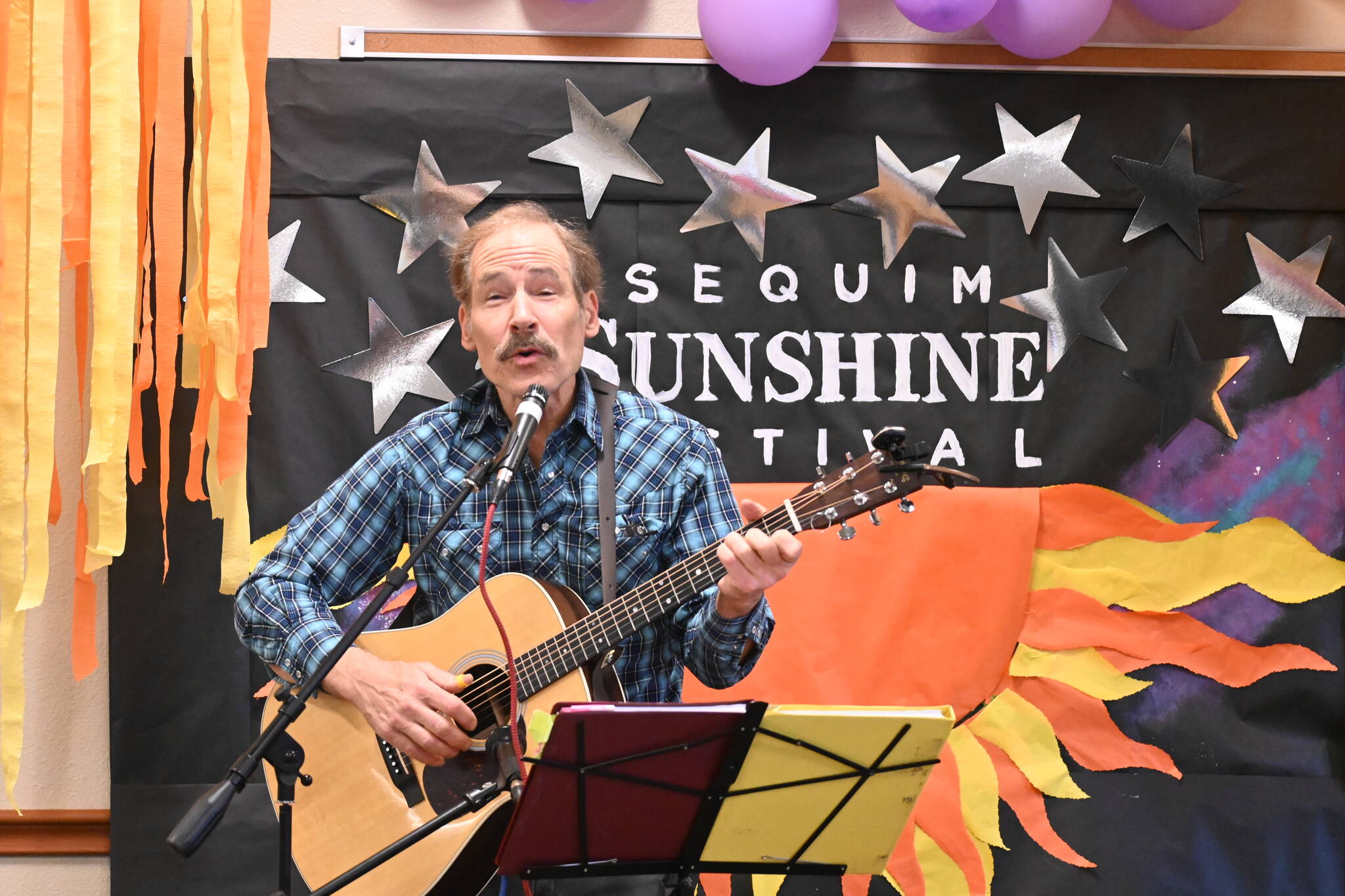 Tom Schindler entertains the Sunshine Market audience inside Guy Cole Event Center on March 4. Wintry weather forced festival organizers to shift music acts to the center and nearby Trinity United Methodist Church.