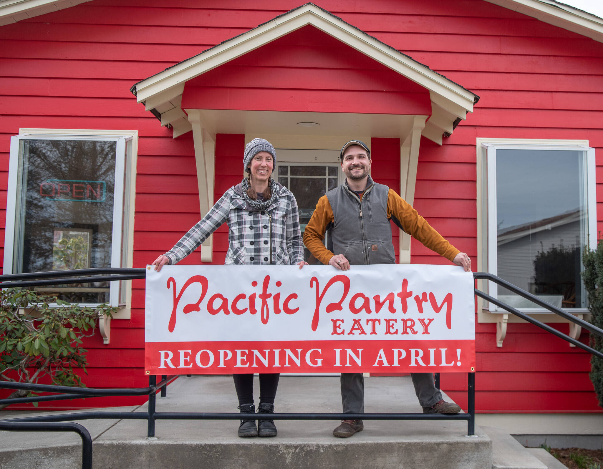 Sequim Gazette photo by Emily Matthiessen / Leslie and John Pabst hold up their new sign on the eve of the reopening of the Pacific Pantry, a eatery/deli that was a local staple for eight years before closing last year.