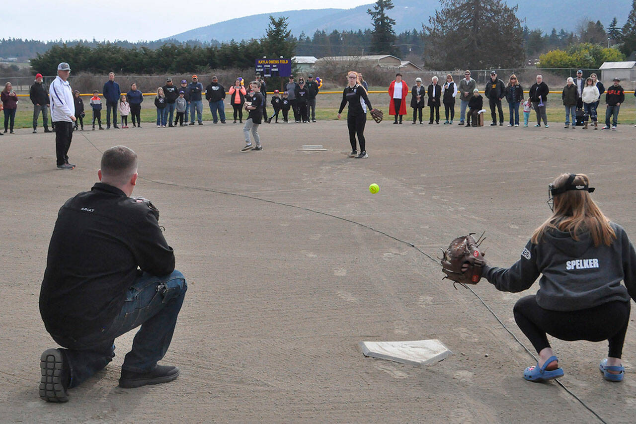 Sequim Gazette photo by Matthew Nash/ Liam, 11, and Nevaeh Owens, 14, throw out ceremonial pitches caught by their dad Cody Owens and friend Lucy Spelker at a dedication ceremony naming a field after their mom Kayla Owens on March 19 at the Sequim Little League’s James Standard Park.