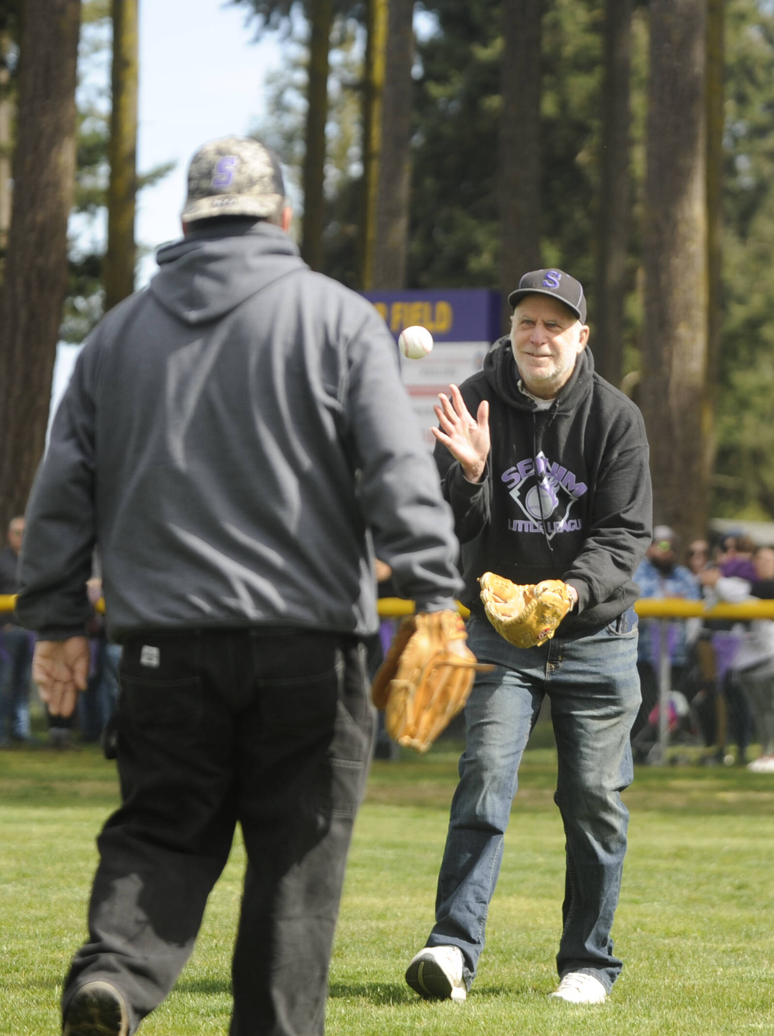 Volunteer Kris Lether, right, gets the ball back from Tony Knapp after throwing out the first pitch at the Sequim Little League Opening Day event on Saturday.