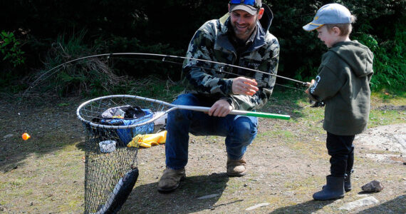 Craig Larson helps his 3-year-old son Barrett net a rainbow trout during Kids Fishing Day on April 23. It was Barrett’s first catch ever, Larson said. (Matthew Nash/Olympic Peninsula News Group)