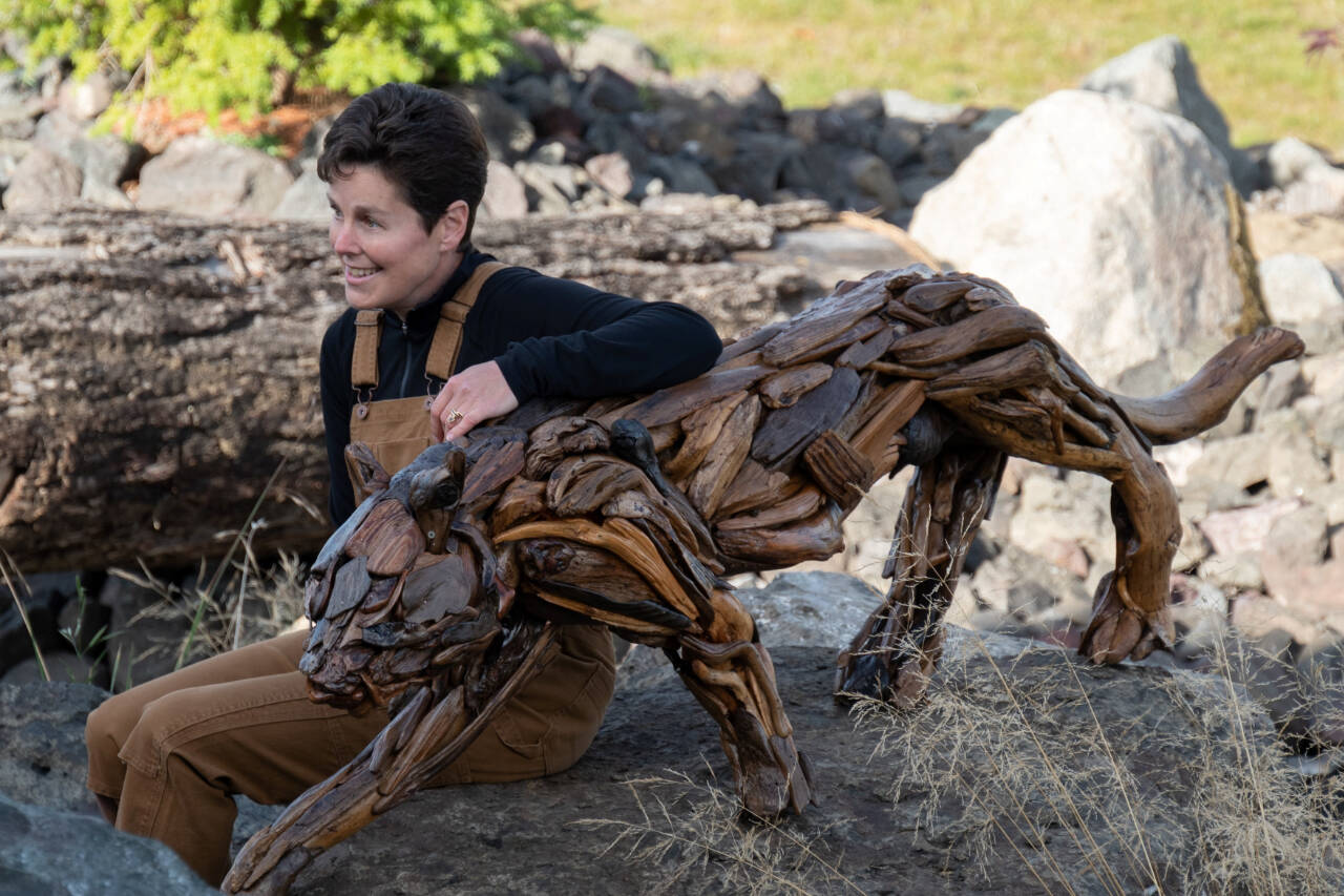 Photo courtesy of Molly Omann / Driftwood artist Molly Omann, pictured here with her life-sized cougar sculpture, will have her art on display at Sequim Museum & Arts in April and during the First Friday Art Walk on April 7.