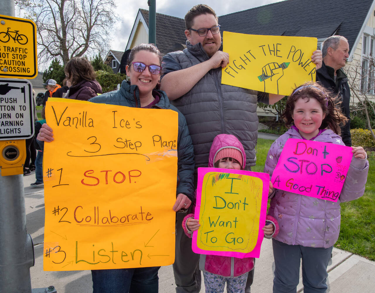 Sequim Gazette photo by Emily Matthiessen / Wynn and Jared Hannam, joined here by youngsters Nora (center) and Ellie, protest on April 17 the reconfiguration of Sequim’s elementary schools. The Hannams live within walking distance of Helen Haller Elementary School. “They want to be together at school,” Jaren Hannam said. “They shouldn’t have to ride the bus an hour when they live within walking distance.”