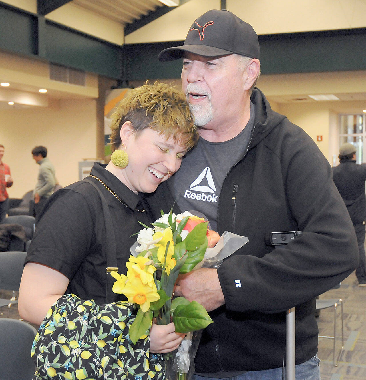 Photo by Keith Thorpe/Olympic Peninsula News Group / Jaiden Dokken, Clallam County’s first poet laureate, receives a hug and flowers from their father Mark Dokken of Port Angeles after Jaiden was inaugurated to their two-year post at the Port Angeles Library on April 18.