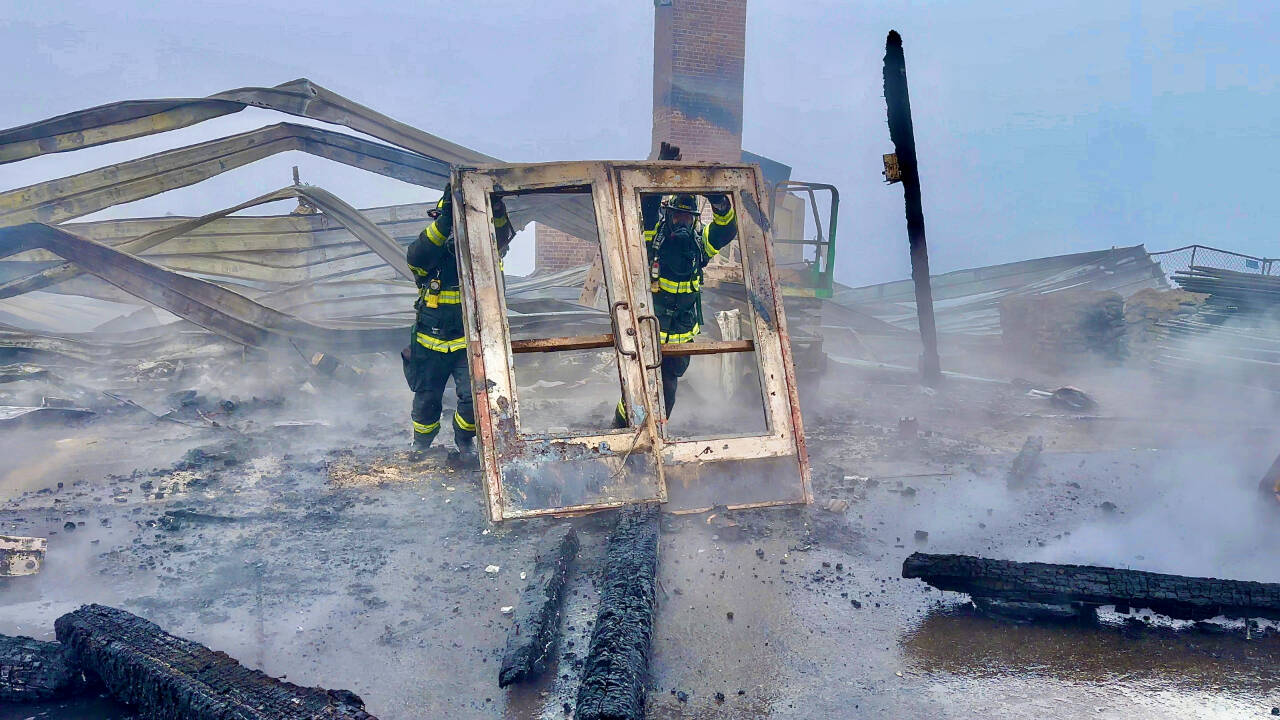 Photo by Jay Cline/Clallam County Fire District 2 / Firefighters from Clallam 2 Fire-Rescue and the Port Angeles Fire Department remove a door from the remains of the Olympic National Park Day Lodge on May 7.