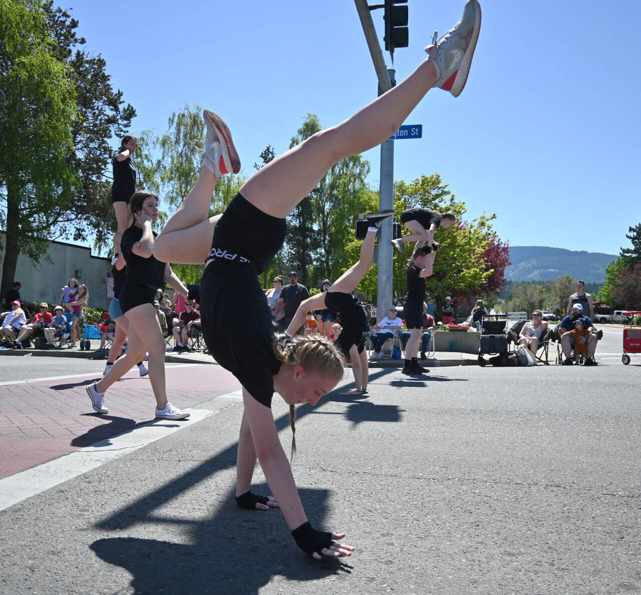 At left: Keylee Disinski walks on her hands down Washington Street as she and fellow Sequim Acrobatics athletes perform at the Sequim Irrigation Festival Grand Parade on May 13.