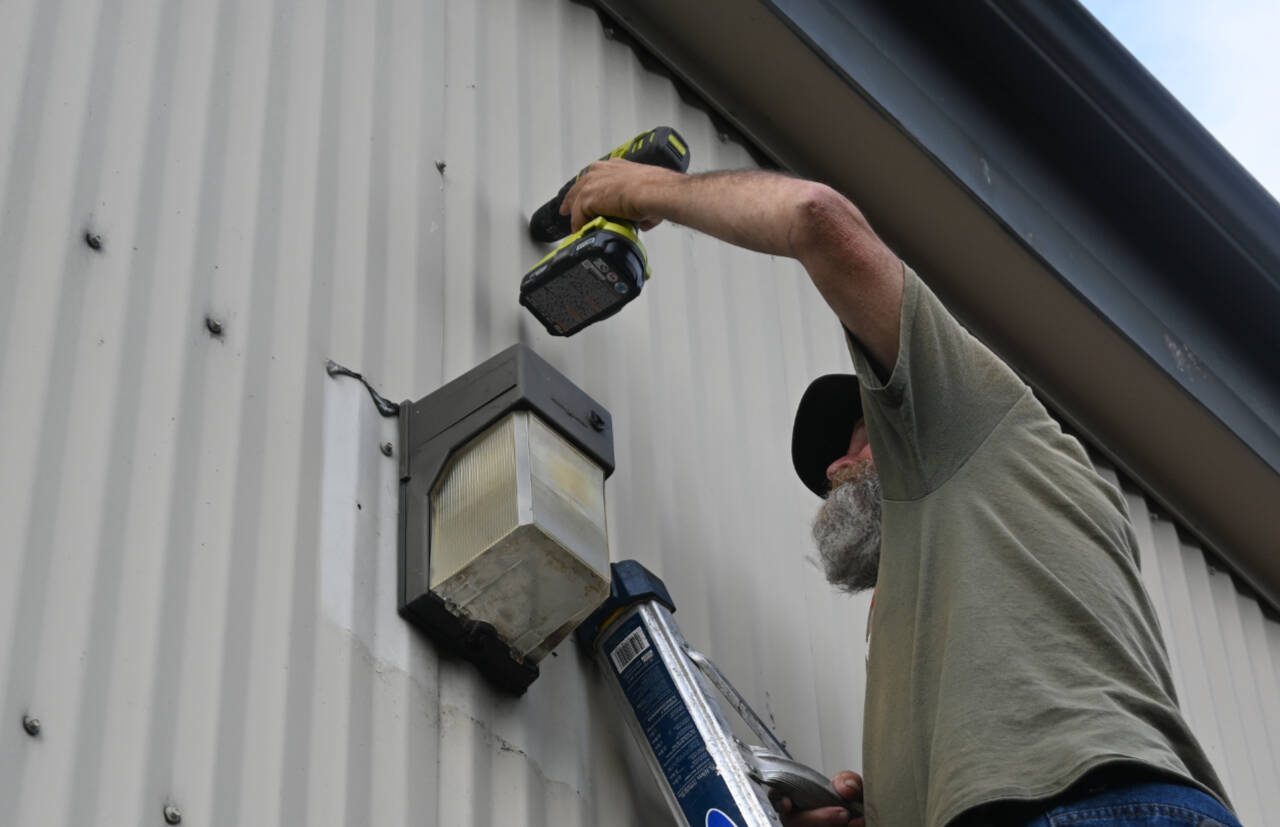 Michael Murphy of Olympic TV & Tech prepares for installation of a security camera at Serenity House Store in Sequim.