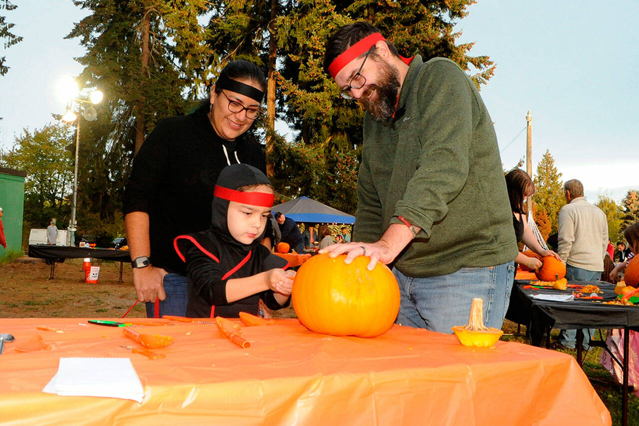 Sequim Gazette file photo by Matthew Nash/ 
Ninja Aiden Havel-Beristain carves a pumpkin with his ninja parents Gabriela Beristain-Havel and Tim Havel at the Sequim Prairie Grange’s Trunk-or-Treat in 2022. The event returns on Oct. 28.