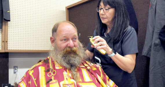 U.S. Navy veteran Brent Brant of Port Hadlock gets a haircut from Susan Gile, owner of Benny's Barbershop in Sequim, during Thursday's Port Angeles Stand Down at the Clallam County Fairgrounds. The event was designed to provide direct services and connect veterans to a variety of assistance organizations, as well as offer clothing, medical services and a meal. (Keith Thorpe/Peninsula Daily News)