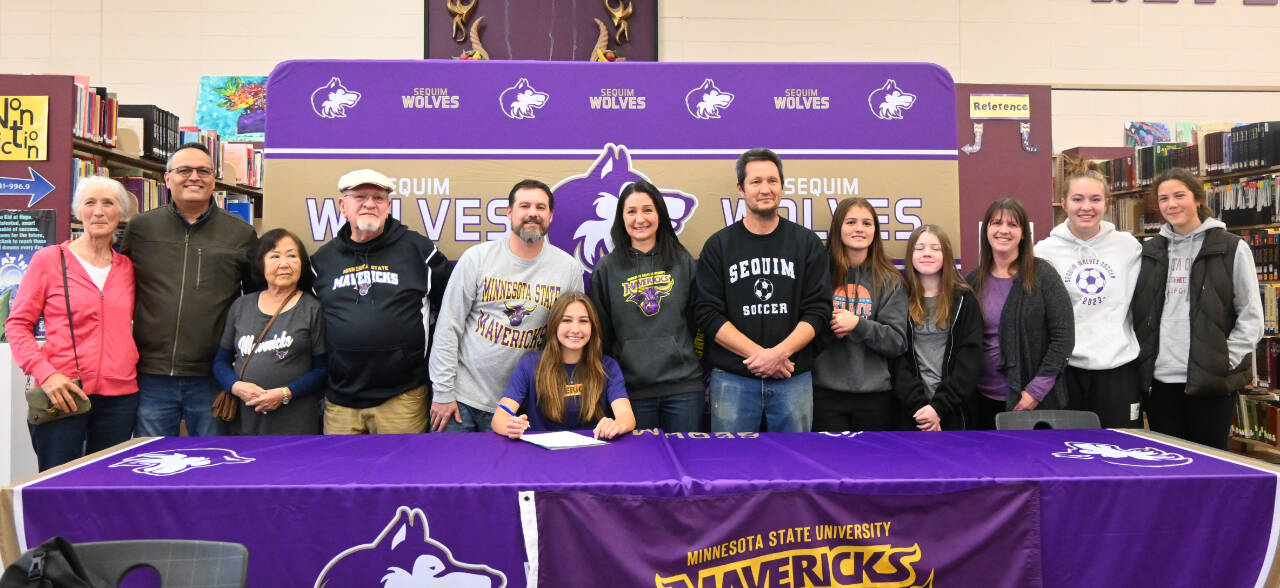 Sequim Gazette photo by Michael Dashiell / Friends, family and coaches join Sequim High senior Taryn Johnson, center, as she signs a letter of intent to play for Minnesota State University, Mankato, on Nov. 8 at the SHS library.
