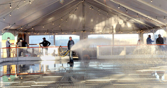 KEITH THORPE/PENINSULA DAILY NEWS
Tommy Robertson of Port Angeles, center, sprays water onto chiller coils that will eventually create the ice skating surface at the Port Angeles Ice Village on Tuesday in downtown Port Angeles.