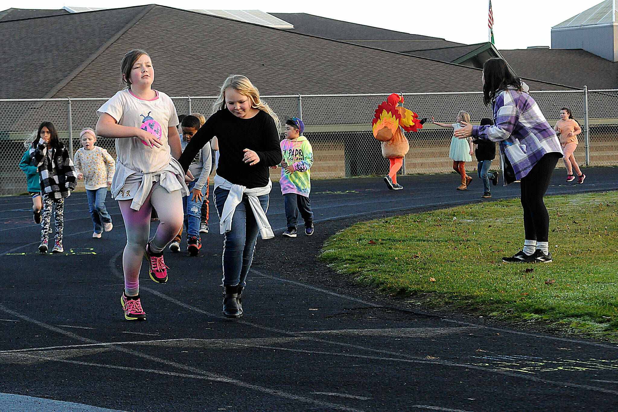 Sequim Gazette photo by Matthew Nash/ Third grade pals Evelyn Moore, left, and Averyonna Rowden skip along as they do laps together at Helen Haller Elementary’s Turkey Trot on Nov. 22.