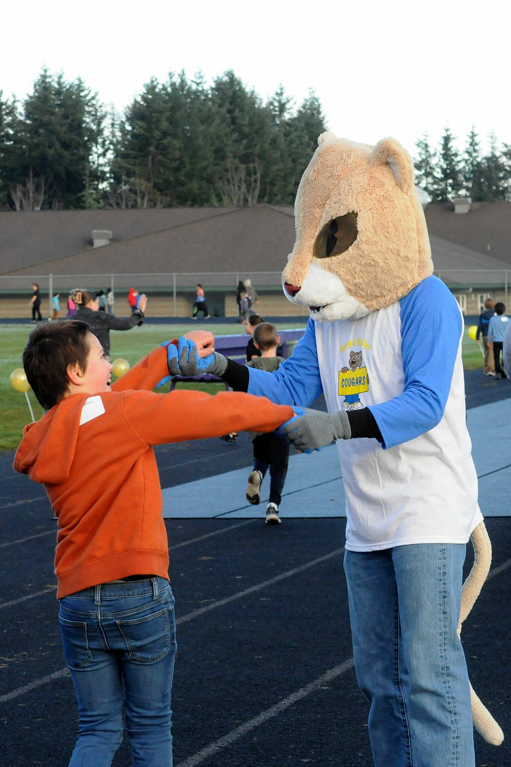 Sequim Gazette fotoğrafı: Matthew Nash/Robert Kistner, ikinci sınıf öğrencisi, Türk Koşusu sırasında Helen Haller İlköğretim Okulu'ndan Calvin Cougar ile dans ediyor.