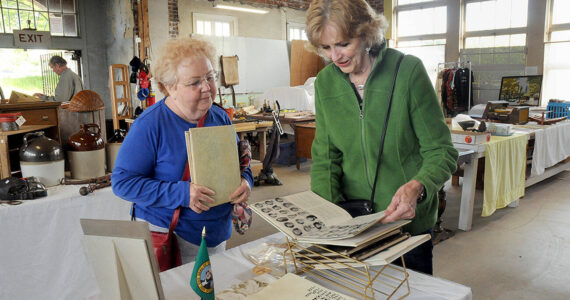 Maureen Sandison, left, and Valle Nevaril, both of Port Angeles, examine high school year books on sale at the North Olympic History Center's Vintage Sale on Saturday at the former Lincoln School in Port Angeles. The sale, which included collectables, vintage clothing, tools and other items, was designed to benefit the center's programs and operations. (Keith Thorpe/Peninsula Daily News)