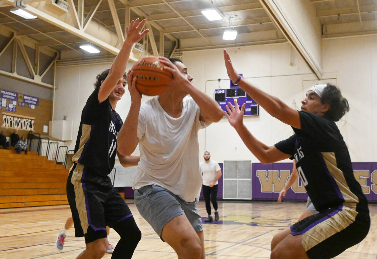 Sequim Gazette photo by Michael Dashiell / 2023-24 Sequim High varsity players Charlie Grider, left, and Lars Wiker, right, guard former Olympic League MVP Alex Barry (class of 2015) in the school’s annual alumni game on Nov. 24.