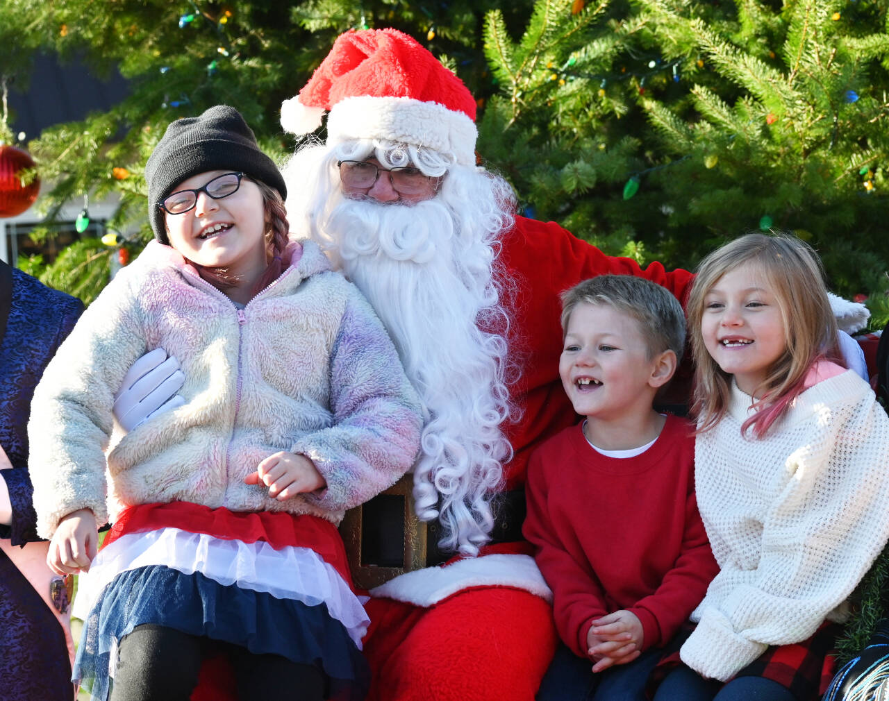 Sequim Gazette photo by Michael Dashiell / from left, Destiny, 7, Seth, 4, and Nora Summers, 6, of Sequim enjoy a moment with Santa Claus — who looks suspiciously like Stephen Rosales — at the Sequim Hometown Holidays event on Nov. 25.